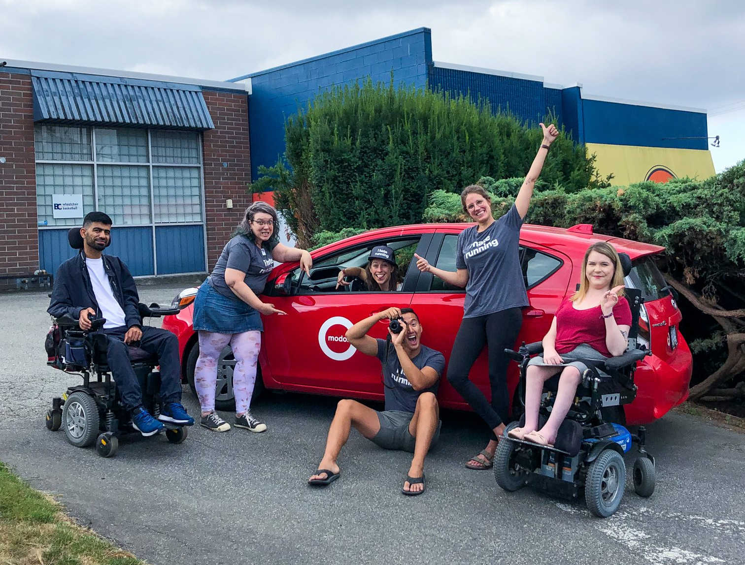 modo_whistler car a group photo of people posing in front of a red Modo car. People in the group photo are able bodied and in wheelhcairs.